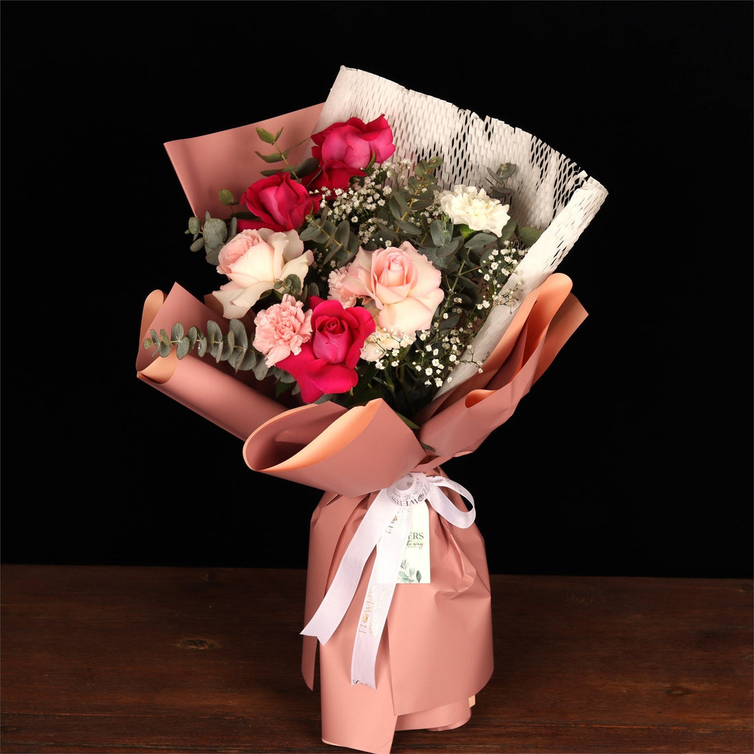 Bouquet mixing red, pink and white roses in blush wrap, showing what the colours say
