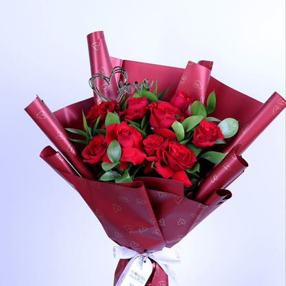 Express your love this Valentine’s Day with our elegant 10 Red Roses Bouquet, beautifully arranged with fresh ruscus leaves and a romantic acrylic heart, all wrapped in luxurious red wrapping. This classic Valentine’s bouquet is perfect for romantic surprises, anniversaries, and meaningful love gestures, making it an unforgettable gift that speaks from the heart.
