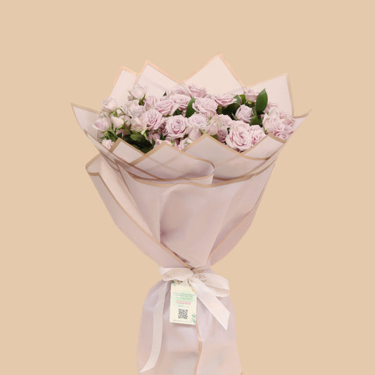 Violet Touch is a soft bouquet of lavender baby spray roses, arranged in a simple and elegant style that captures calm beauty. Wrapped in matching purple paper, it offers a refined and graceful look – perfect for heartfelt gifts, subtle celebrations, or just because.