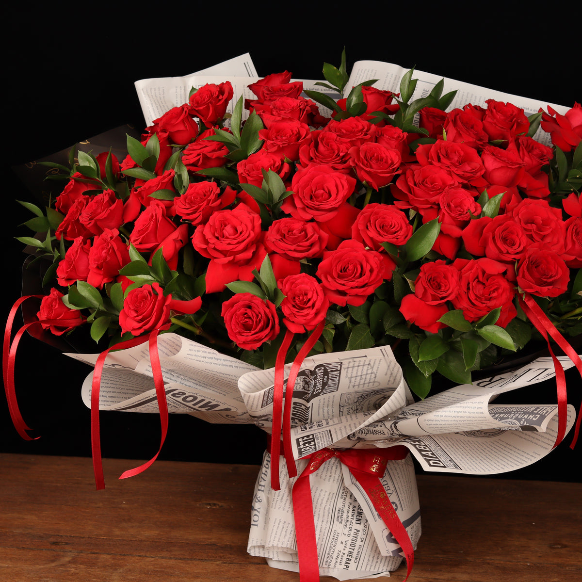 Vintage Love Story – 50 red roses with ruscus in newspaper-style paper, alternate view, Valentine's Day flower delivery Dubai