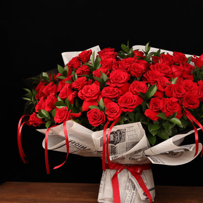 Vintage Love Story – 50 red roses with ruscus in newspaper-style paper, alternate view, Valentine's Day flower delivery Dubai